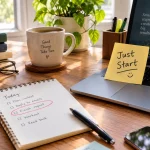 Messy desk with a “Just Start” sticky note, laptop, and one circled task on a notepad